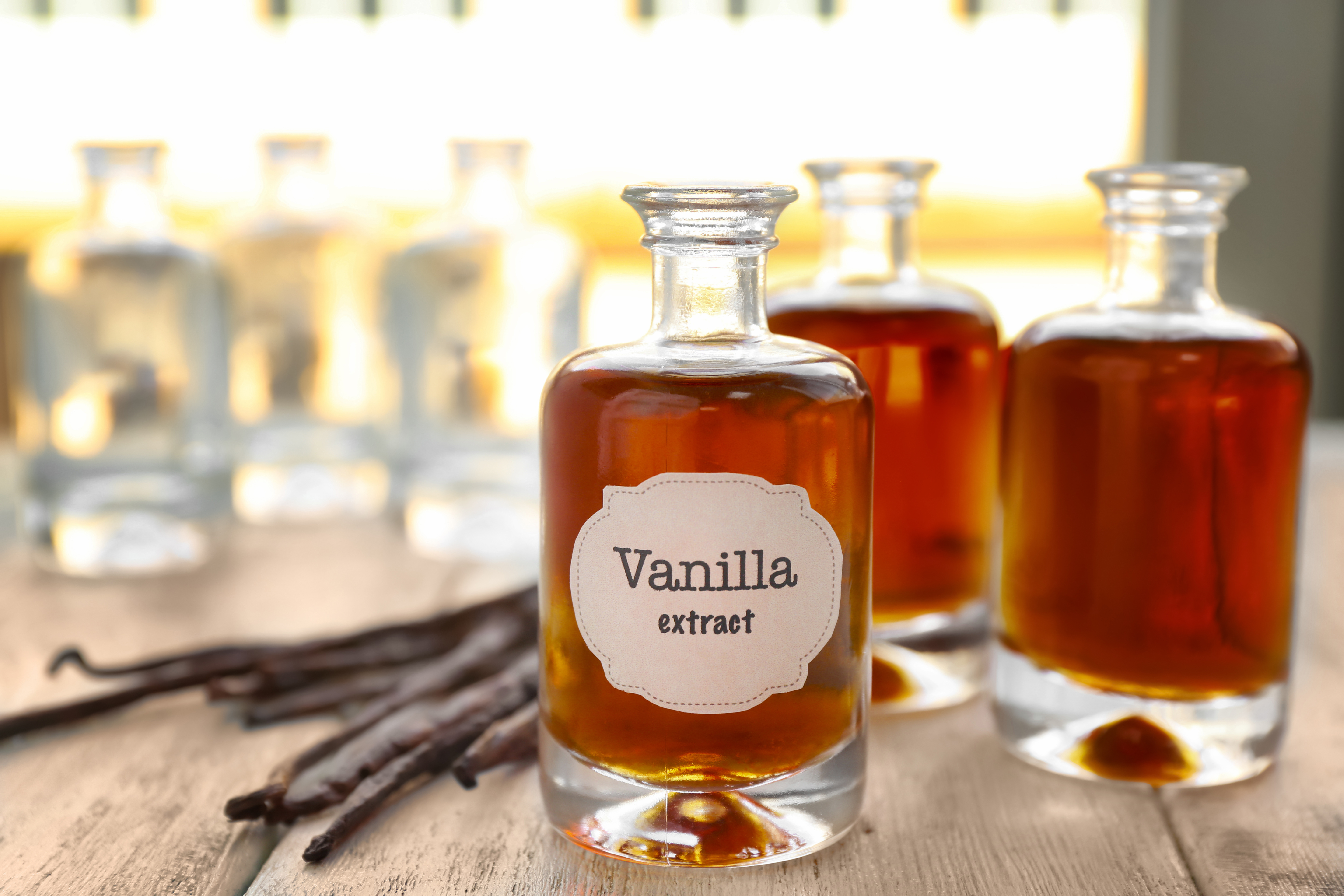 Amber vanilla extract in glass bottles with vanilla beans